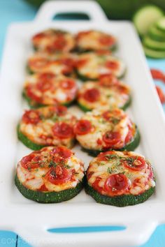 mini zucchini pizzas on a platter with cucumbers in the background