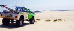 a green and white truck in the sand