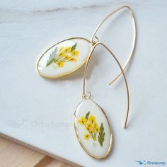 two earrings with yellow flowers on them sitting on a table