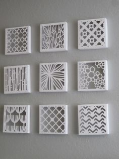 six white paper cut designs on a gray wall