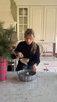 a woman mixing something in a bowl on the kitchen counter