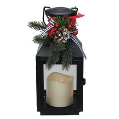 a candle is sitting on top of a black box with pine cones and red berries