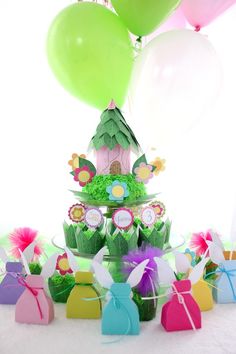 a table topped with lots of cupcakes covered in green frosting and balloons