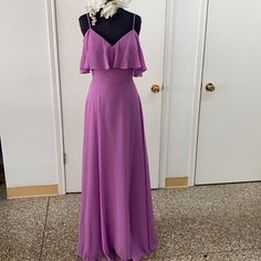 a purple dress is displayed on a mannequin in front of a door with white flowers