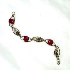 This is part of Chairish’s Costume Jewelry assortment.  1930s Art Deco 12k gold over sterling link bracelet. This delicate offering presents open elliptical links with smooth connectors, alternating heart-shaped leaves with emerald-cut ruby-colored  crystals. The workmanship is simple and meticulous, and the stones are vivid and evocative. Elegant and subtle, but with a hint of exuberance in the ruby crystals, this beauty is equally at home with a white shirt and jeans or a classic LBD. Not sign Engraved Heirloom Metal Jewelry, Antique Red Bracelet For Formal Occasions, Red Antique Bracelet For Formal Occasions, Vintage Jewelry With Rectangular Links For Gift, Elegant Sterling Silver Jewelry With Vintage Charm, Formal Engraved Jewelry With Rectangular Links, Heirloom Jewelry With Oval Jewels, Heirloom Oval Jewelry With Jewels, Vintage Red Gemstone Bracelets