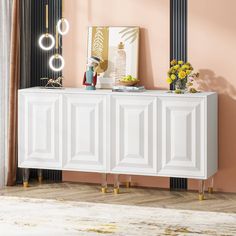 a white sideboard with gold legs in a pink living room, next to a mirror