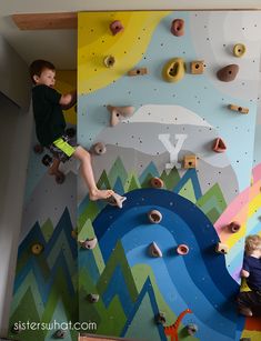 two young boys climbing up the side of a wall with colorful rock art on it