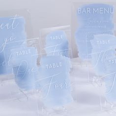 blue watercolored place cards are displayed on clear acrylic stands