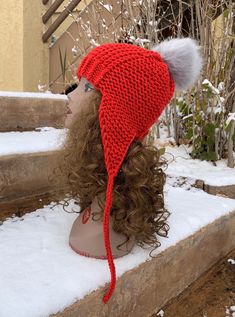 a woman wearing a red knitted hat on top of snow covered steps