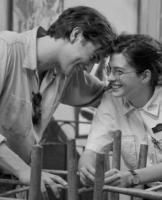 two people standing next to each other near a fence