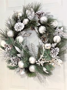 a christmas wreath with pine cones and silver baubies on the front door,