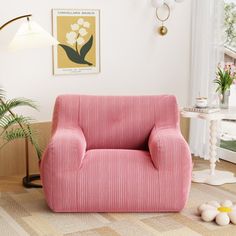 a pink chair sitting in a living room next to a lamp and potted plant