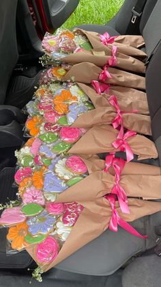 flowers are wrapped in brown paper and tied with pink ribbon on the back seat of a car