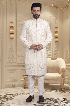 This Mens Sherwani features a layered design. Expertly crafted for grooms, Features stunning red accents to add a touch of traditional elegance to your special day. Exude confidence and style as you walk down the aisle in this expertly designed sherwani. Transitional Season Fitted Sherwani For Groom, Long Traditional Wear For Groom On Eid, Traditional Fitted Sherwani For Groom, Elegant Traditional Wear For Groom On Diwali, Designer Sherwani With Dabka Work For Groom, Designer Sherwani With Intricate Embroidery For Groom, Designer Traditional Wear With Resham Embroidery For Groom, Designer Intricately Embroidered Sherwani For Groom, Elegant Bandhgala With Cutdana For Groom