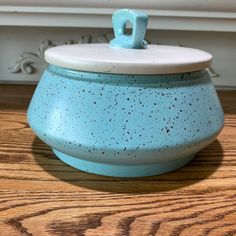 a blue bowl with a white lid on a wooden table