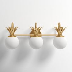 three white balls are hanging from a gold metal bar with pineapples on it