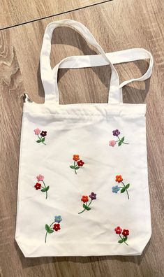 a white bag with flowers on it sitting on a wooden floor next to a pair of scissors