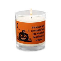 a candle with an orange label on it that says darkness flies across the land, the midnight hour is close at hand