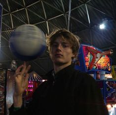 a man is spinning a ball on his finger at an indoor game show in the dark