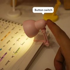 a person is holding a pink light in front of a notebook with writing on it