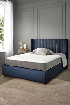 a bed with a blue upholstered headboard and foot board in a bedroom