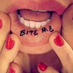 a woman with red nails holding her face up to her mouth and the words bite me written on it