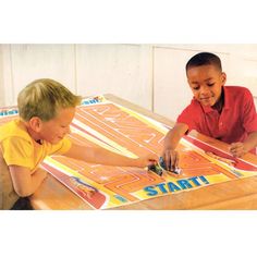 two young boys playing a game on a wooden table with the words start written in large letters