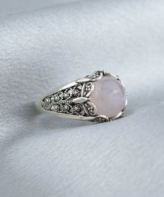 Elevate your style with this stunning Handmade Filigree Art Rose Quartz Gemstone Women Silver Cocktail Statement Ring. The 10mm cabochon round-cut Rose Quartz gemstone set in an elegant silver band measures 13.50mm in length and width, creating a beautiful contrast between the soft pink hues of the gemstone and the silver metal. Crafted with intricate details that showcase the beauty of filigree, an ancient art form originating from Mesopotamia and Anatolia, this exquisite ring is a true work of Elegant Pink Cabochon Rings, Elegant Silver Rings With Rose Design, Elegant Pink Rose Quartz Crystal Ring, Elegant Cabochon Ring With Round Stone, Elegant Adjustable Rose-colored Ring, Elegant Rose Gold Sterling Silver Crystal Ring, Rose Gold Sterling Silver Crystal Ring, Sterling Silver Rose Gold Crystal Ring, Rose Quartz Crystal Promise Ring