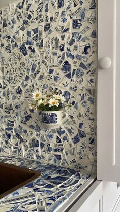 a blue and white tile backsplash with flowers in a vase on the counter