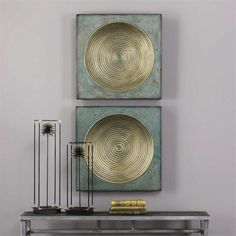 two metal art pieces on a wall above a table