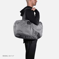 a man is carrying a large gray duffel bag