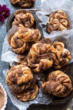 cinnamon buns are sitting on wax paper in the middle of some muffins