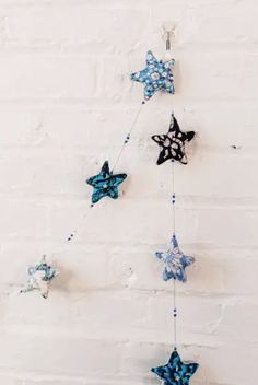 blue and black stars hanging from a white brick wall