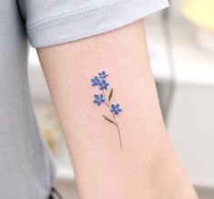 a small blue flower tattoo on the arm