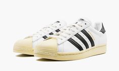 White leather/rubber Superstar low-top sneakers from adidas featuring round toe, gold-tone logo lettering, front lace-up fastening, contrasting heel counter, flat rubber sole and signature three-stripe logo.  These styles are supplied by a premium sneaker marketplace.  Stocking only the most sought-after footwear, they source and curate some of the most hard to find sneakers from around the world. . White Black Shoes, Stadium Goods, Adidas Samba Sneakers, Adidas Superstar Sneaker, White Leather, Low Top, Lace Front, Black Shoes, Top Sneakers