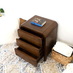 a wooden table with three drawers and a basket on the floor in front of it