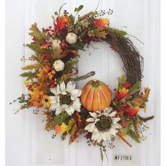 a wreath with pumpkins and flowers on the front door