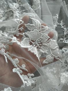 a person holding something in their hand with white lace on it's sides and flowers on the other side