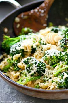 broccoli and pasta in a skillet with a wooden spoon on the side