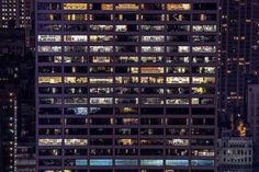 the top of a tall building with many windows lit up at night in new york city