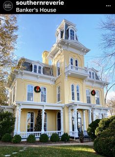 a large yellow house with christmas wreaths on the front