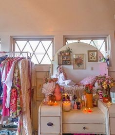 a woman sitting on top of a dresser in front of a mirror next to candles