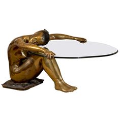 a bronze figurine sitting on top of a glass table