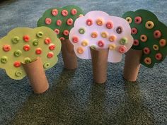 four trees made out of toilet paper with donuts on them sitting on the floor