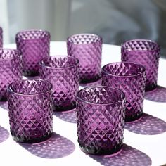 many purple glass cups sitting on top of a table