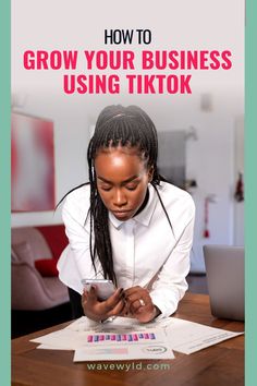 a woman sitting at a table looking at her phone with the text how to grow your business using tiktok