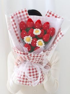 a woman holding a bouquet of strawberries and daisies