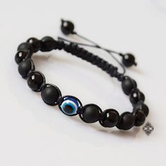 "This Evil Eye bracelet is all about a clean and elegant design. Featuring two types of Black Onyx beads - matte and shiny - and an evil eye protection bead as its centerpiece, this eye bracelet is strung on a waxed cord and is finished off with an adjustable closure. The Evil Eye symbol is an ancient talisman that is believed to ward off evil and protect against misfortune and bad luck. The black color is believed to protect against negativity. Black Onyx is said to help release negative emotio Modern Black Round Bead Bracelets, Modern Handmade Black Bracelets, Modern Black Bracelets With 8mm Beads, Modern Black Bracelet With 8mm Beads, Black Adjustable Bracelets, Adjustable Black Bracelets, Adjustable Black Round Bracelets, Adjustable Black Hand-strung Evil Eye Bracelet, Adjustable Hand-strung Black Evil Eye Bracelet