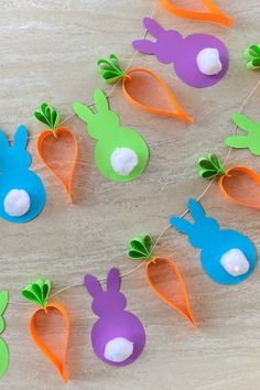 paper carrots and radishes hanging from string on wooden table with white background