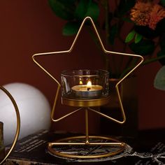 a gold star shaped candle holder with a lit candle in it on top of a table